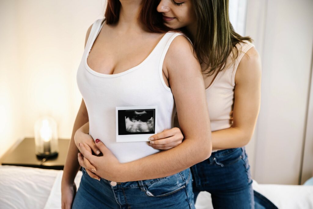 lesbian-couple-holding-ultrasound-scan-baby-near-belly-pregnant-girlfriend-bed (2)